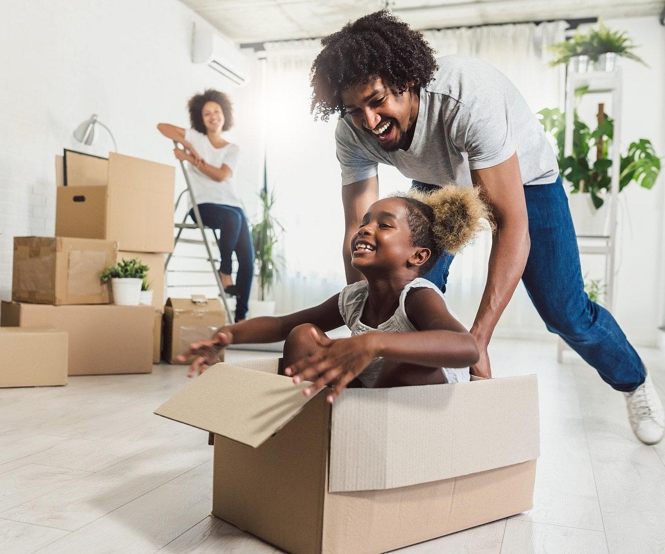 Father pushing daughter in moving box.